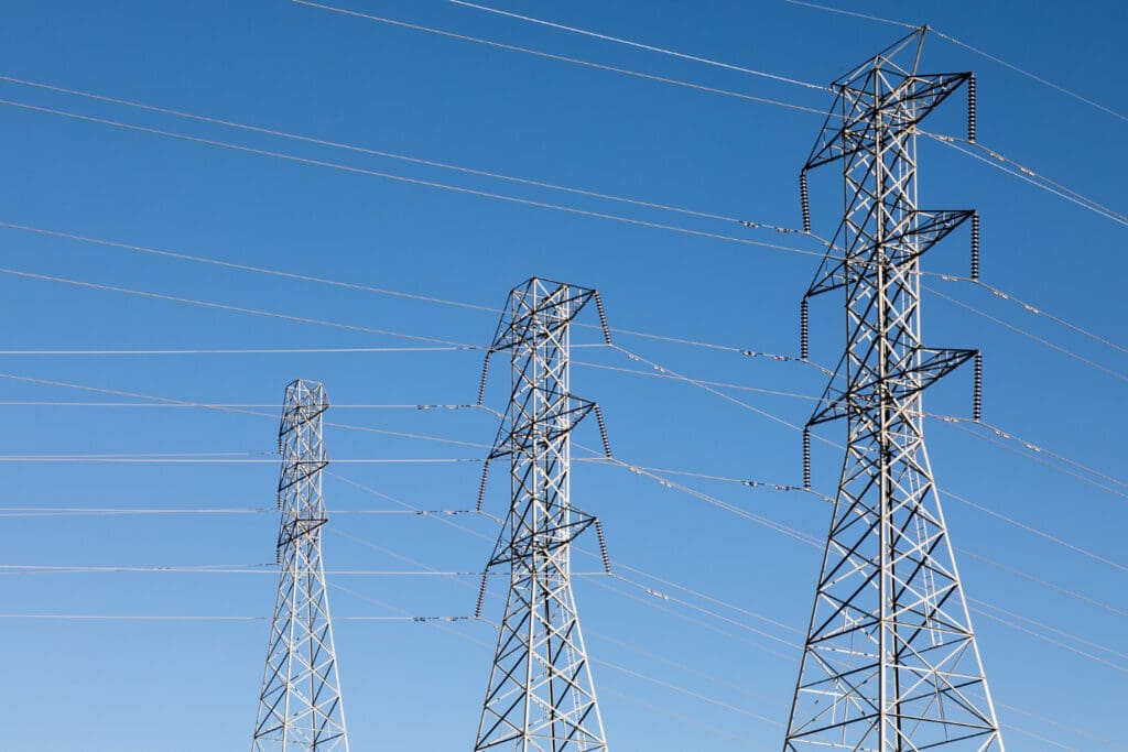 Transmission towers holding power lines, with a clear blue sky in the background